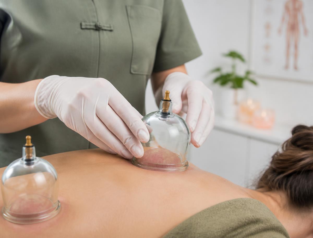 Therapist in gloves applying a glass cupping cup to a patient's back